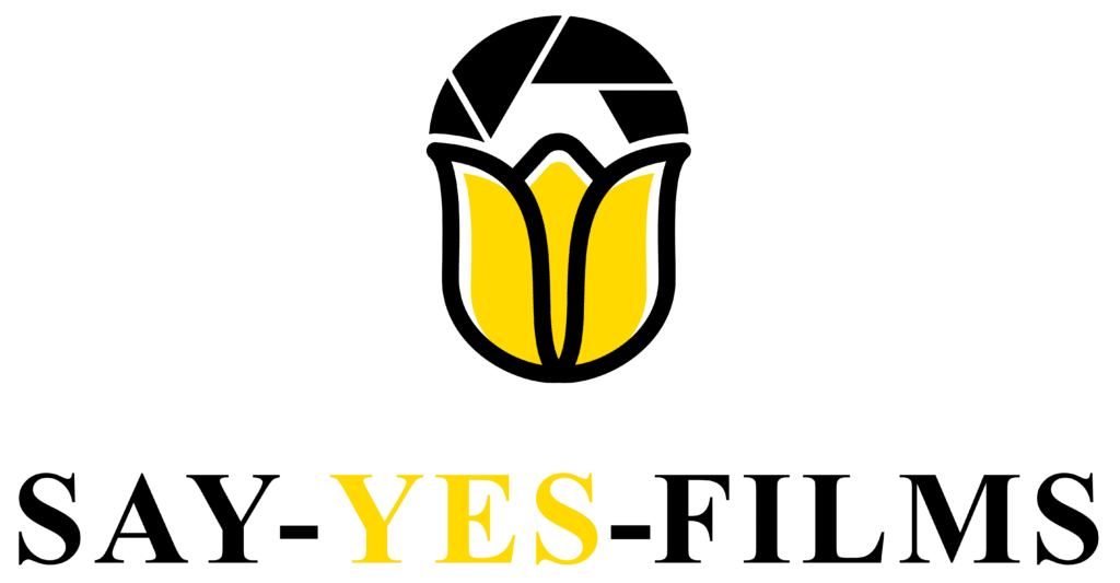 Das Logo von „Say Yes Films“ zeigt eine stilisierte gelbe Tulpe mit schwarzem Umriss und eckiger Spitze, über der in Schwarz der Text „SAY-YES-FILMS“ steht, wobei das Wort „YES“ gelb hervorgehoben ist. Perfekt, um die Magie von Hochzeitsmomenten einzufangen.